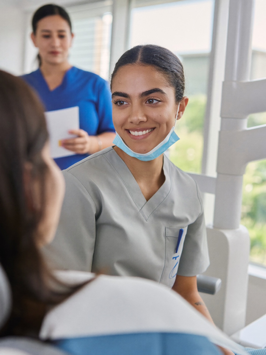 Estudiante de odontología conversando con una paciente en una clínica universitaria